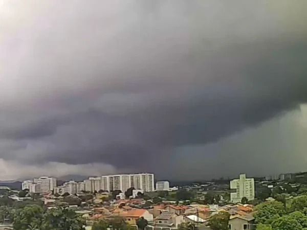 Vista panorâmica de Itaboraí sob forte calor e céu coberto por nuvens cinzentas de tempestade avançando sobre a área urbana