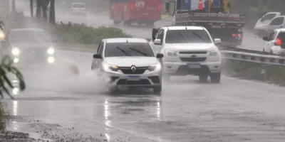 Veículos trafegam sob chuva forte em avenida de Maricá
