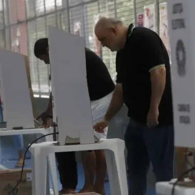 Eleitores chegam a local de votação durante as Eleições 2026 sob regras contra boca de urna e propaganda eleitoral