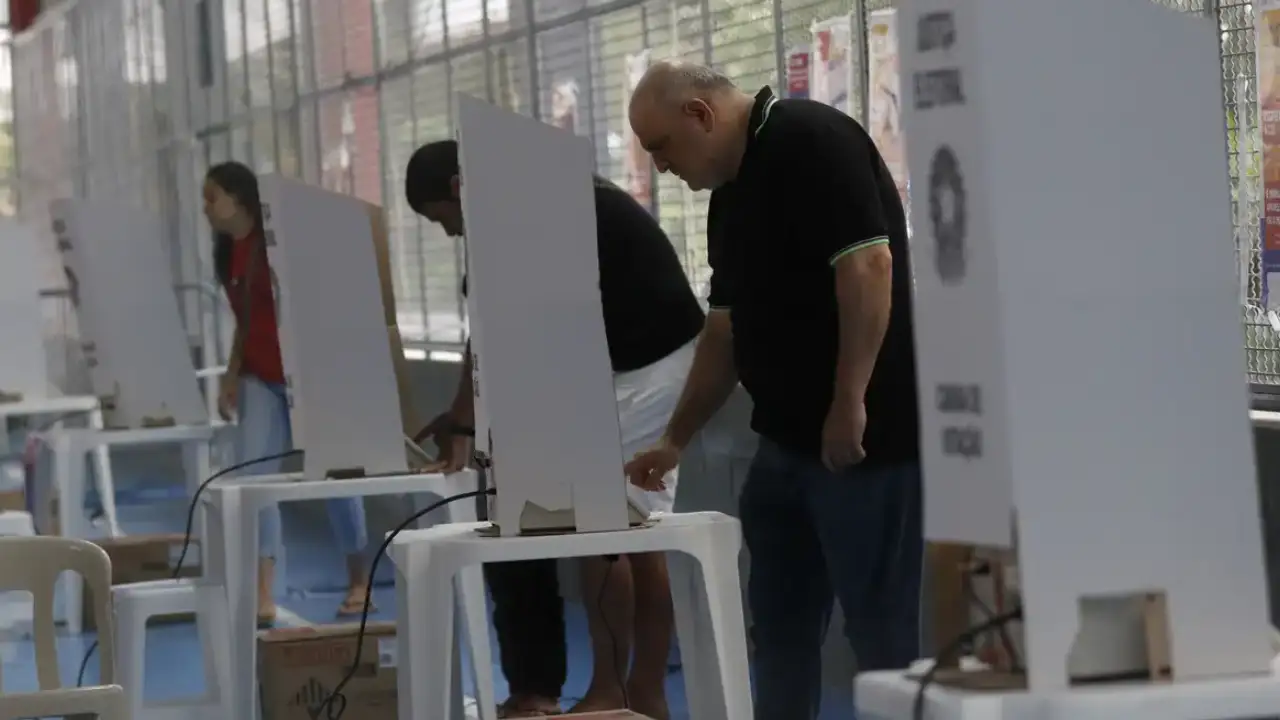 Eleitores chegam a local de votação durante as Eleições 2026 sob regras contra boca de urna e propaganda eleitoral