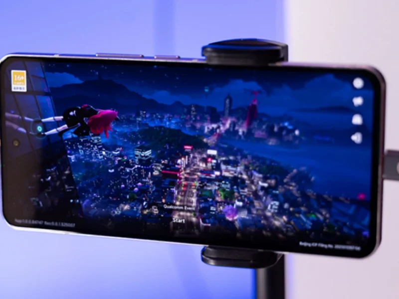 Smartphone em suporte exibindo um jogo durante demonstração de tecnologia Snapdragon.