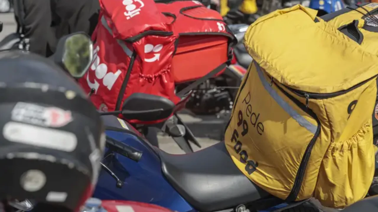 Mochilas de entregadores por aplicativo sobre motocicletas em área urbana