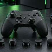 Controle gamer preto com dois direcionais digitais, módulos de botões ABXY e diferentes modelos de analógicos intercambiáveis sobre uma bancada escura.