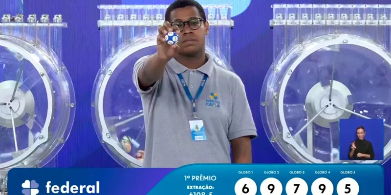 Funcionário da Caixa exibe bola ejetada do globo durante sorteio que formou o resultado completo de todos os prêmios do concurso 6108 da Loteria Federal, referente à Extração de Domingo, 11/10, com todas as dezenas de milhar do 1º, 2º, 3º, 4º, 5º prêmio, bem como premiações derivadas