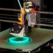 Impressora 3D em funcionamento, produzindo um objeto por camadas de filamento, em reportagem sobre altura de camada variável.
