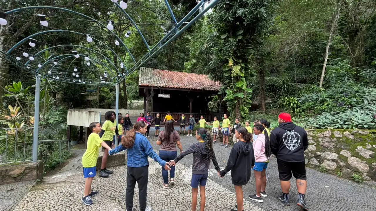 Crianças do Clin Social participam de brincadeira coletiva de mãos dadas, em espaço arborizado durante atividade recreativa em Niterói. Crianças do Clin Social participam de brincadeira coletiva de mãos dadas, em espaço arborizado durante atividade recreativa em Niterói.