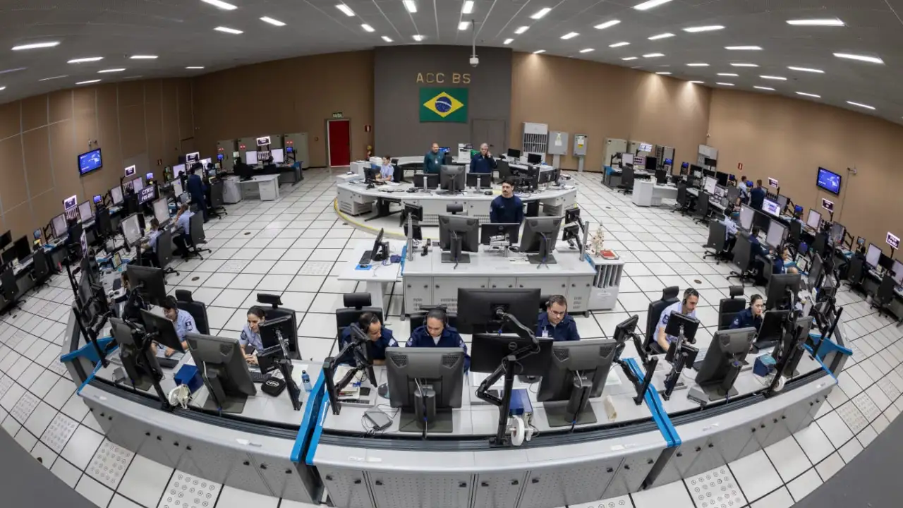 Controladores de tráfego aéreo da FAB trabalham em torre de controle, utilizando rádio e monitores para acompanhar movimentos de aeronaves.