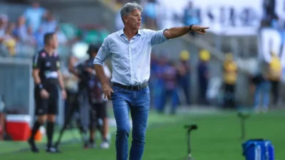 Renato Portaluppi, técnico do Grêmio, aponta para o campo e orienta a equipe à beira do gramado durante partida de futebol.