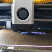 Cabeçote de impressora 3D em funcionamento, ilustrando a formação de camadas e da costura Z durante a extrusão.