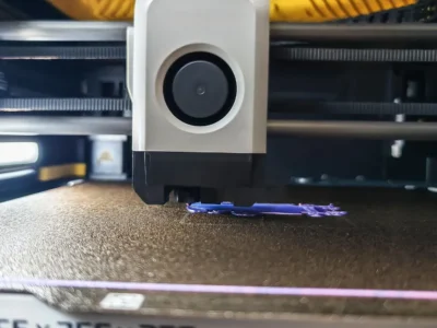 Cabeçote de impressora 3D em funcionamento, ilustrando a formação de camadas e da costura Z durante a extrusão.