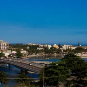 Vista panorâmica de Saquarema, com ponte sobre a lagoa, área urbana, vegetação e praia ao fundo.
