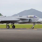 Caça F-39 Gripen de matrícula militar 4100 da Força Aérea Brasileira em uma pista, visto de perfil.