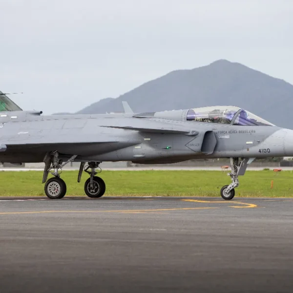 Caça F-39 Gripen de matrícula militar 4100 da Força Aérea Brasileira em uma pista, visto de perfil.