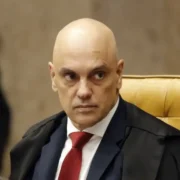 Ministro Alexandre de Moraes, do Supremo Tribunal Federal, sentado no plenário do STF, usando toga preta e gravata vermelha.