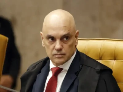 Ministro Alexandre de Moraes, do Supremo Tribunal Federal, sentado no plenário do STF, usando toga preta e gravata vermelha.