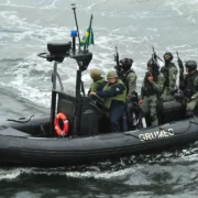 Mergulhadores de combate do GRUMEC, da Marinha do Brasil, participam de treinamento em uma embarcação militar no mar.