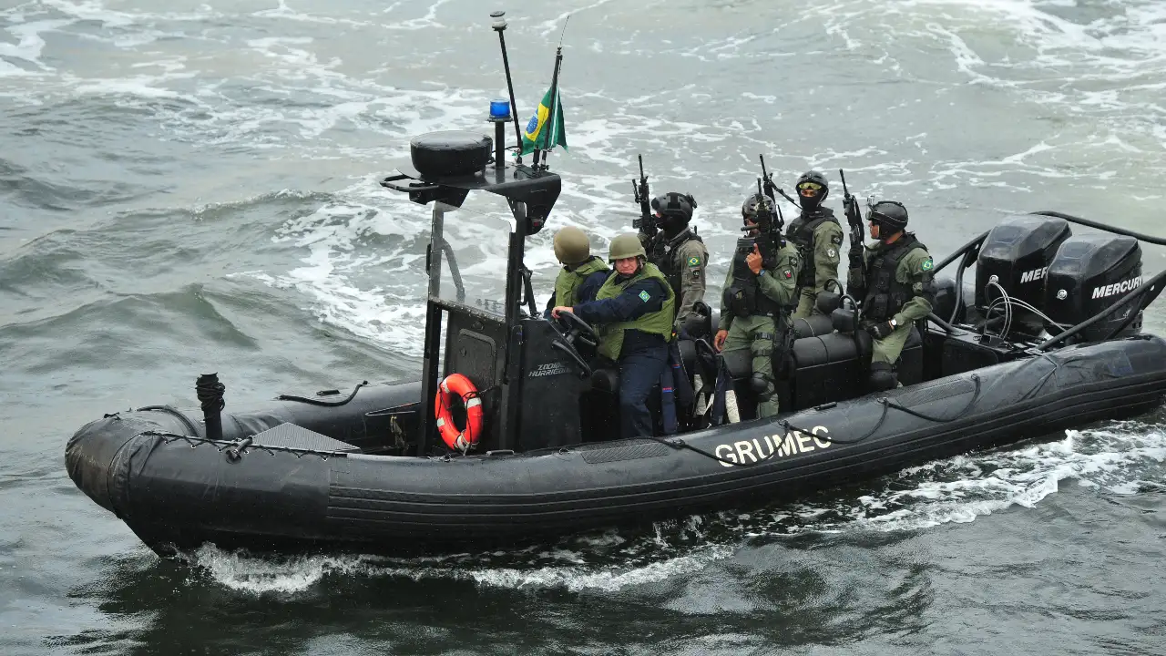 Mergulhadores de combate do GRUMEC, da Marinha do Brasil, participam de treinamento em uma embarcação militar no mar.