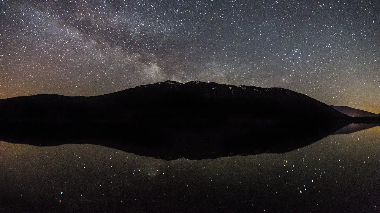Via Láctea sobre montanha com reflexo em lago durante a noite Via Láctea sobre montanha com reflexo em lago durante a noite