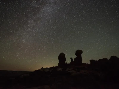 Céu estrelado sobre formações rochosas durante a noite