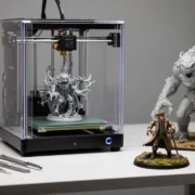 Miniaturas detalhadas produzidas por impressão 3D em resina, com impressora de fotopolimerização ao fundo.