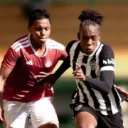 Jogadoras de Internacional e Atlético-MG disputam a bola em partida de futebol feminino.