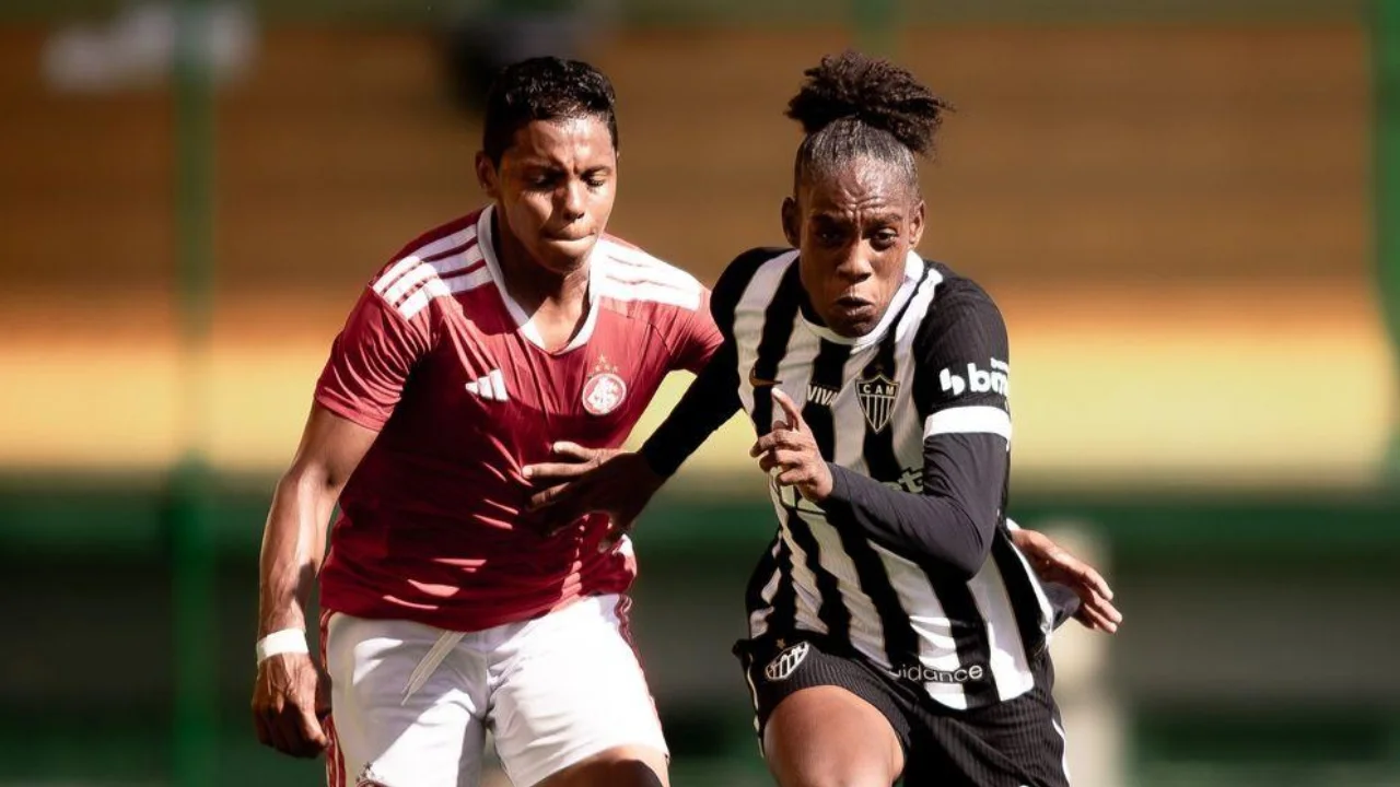 Jogadoras de Internacional e Atlético-MG disputam a bola em partida de futebol feminino.