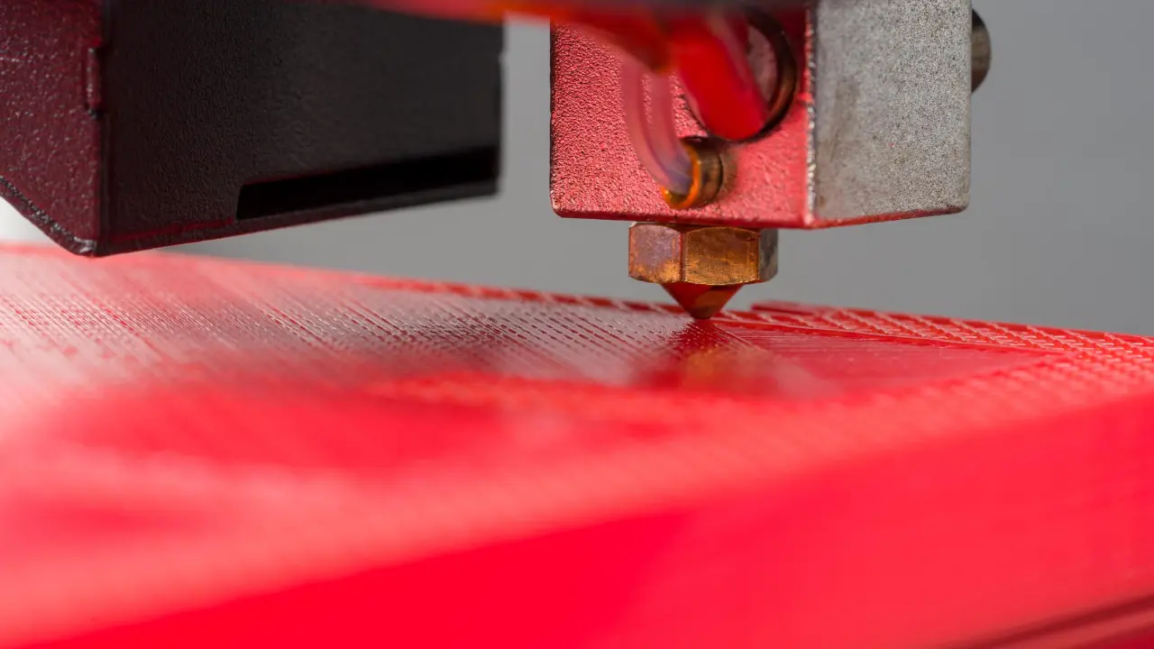 Bico de impressora 3D sobre a superfície de impressão, ilustrando a técnica ironing para melhorar o acabamento de peças. Bico de impressora 3D sobre a superfície de impressão, ilustrando a técnica ironing para melhorar o acabamento de peças.