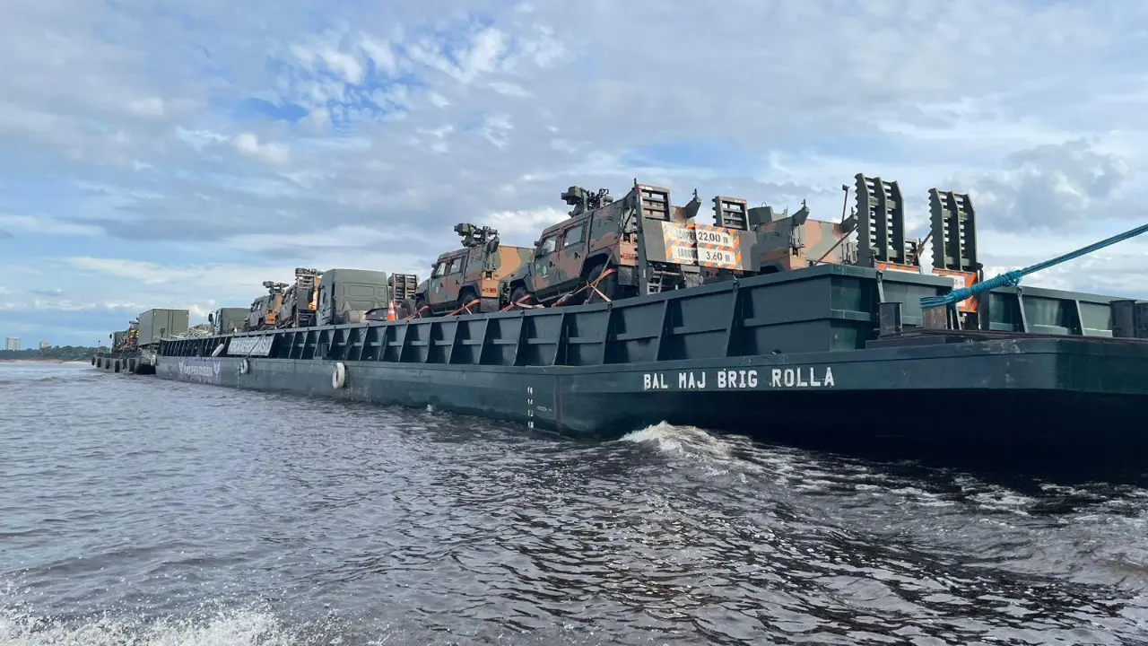 Embarcação militar navegando em rio amazônico durante atividade de transporte e apoio logístico.