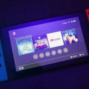 Nintendo Switch com tela ligada e controles Joy-Con, em fotografia ilustrativa sobre jogos digitais.