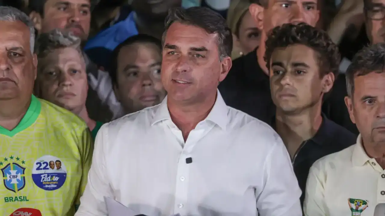 Flávio Bolsonaro, de camisa branca, fala à imprensa diante de um grupo de apoiadores após o segundo turno das eleições presidenciais.