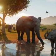 Elefante adulto e filhote dentro de um lago em habitat natural de Planet Zoo 2, com outros animais ao fundo.