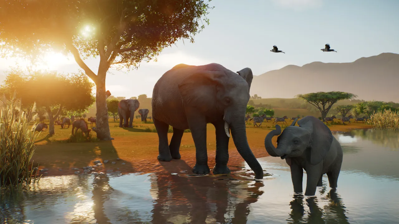 Elefante adulto e filhote dentro de um lago em habitat natural de Planet Zoo 2, com outros animais ao fundo.