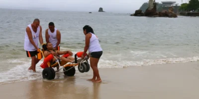 Praia de Icaraí, em Niterói, com pessoas na areia e vista para o Pão de Açúcar, no Rio de Janeiro.