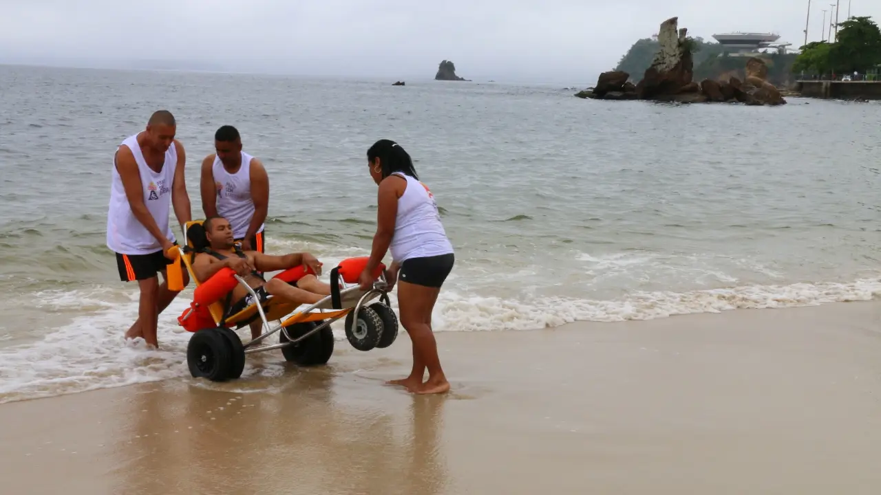 Praia de Icaraí, em Niterói, com pessoas na areia e vista para o Pão de Açúcar, no Rio de Janeiro.