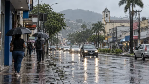 Pedestre com guarda-chuva caminha sob chuva em rua molhada