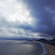 Praia de Piratininga, em Niterói, com nuvens escuras no céu, ilustrando a previsão de chuva e ventos fortes.