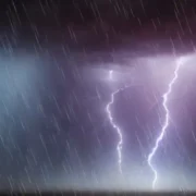Raios iluminam o céu escuro durante uma tempestade, com chuva intensa e nuvens carregadas.