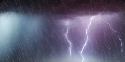 Raios iluminam o céu escuro durante uma tempestade, com chuva intensa e nuvens carregadas.