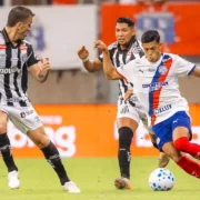 Jogador do Bahia disputa a bola com dois atletas do Santos durante partida do Campeonato Brasileiro.