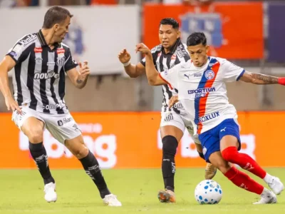 Jogador do Bahia disputa a bola com dois atletas do Santos durante partida do Campeonato Brasileiro.