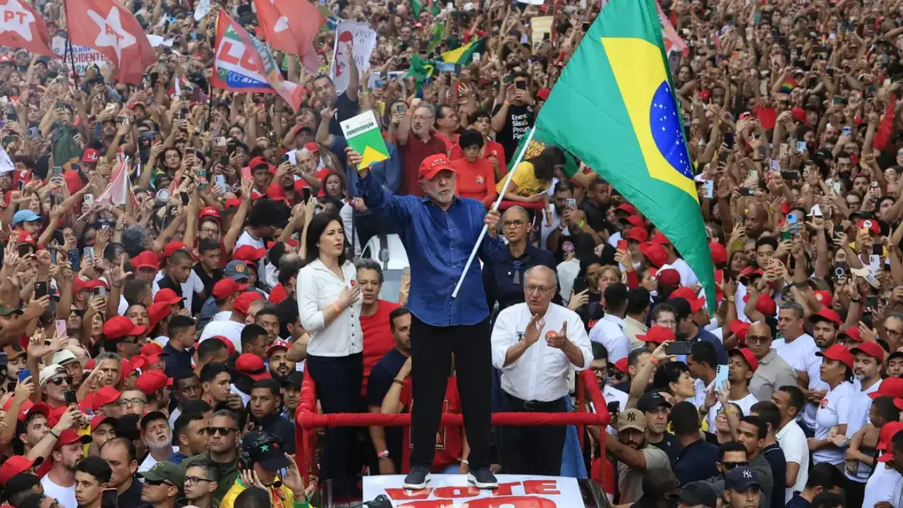 Presidente Lula ergue a bandeira do Brasil e um exemplar da Constituição diante de uma multidão de apoiadores durante ato de campanha. Presidente Lula ergue a bandeira do Brasil e um exemplar da Constituição diante de uma multidão de apoiadores durante ato de campanha.