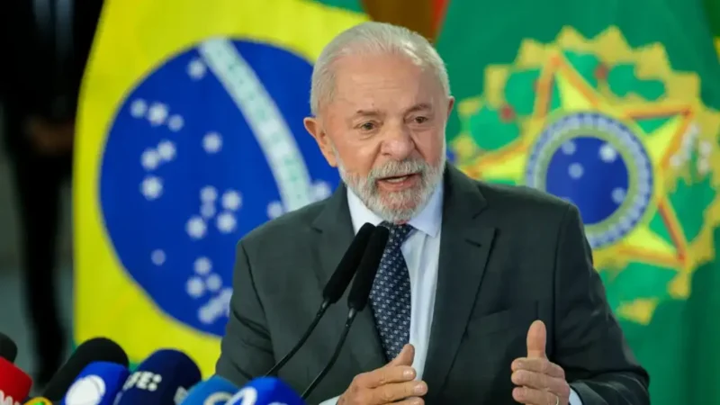 Pronunciamento diante de microfones, com bandeiras do Brasil ao fundo, em cerimônia oficial.