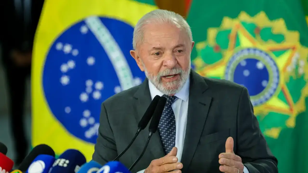 Pronunciamento diante de microfones, com bandeiras do Brasil ao fundo, em cerimônia oficial.